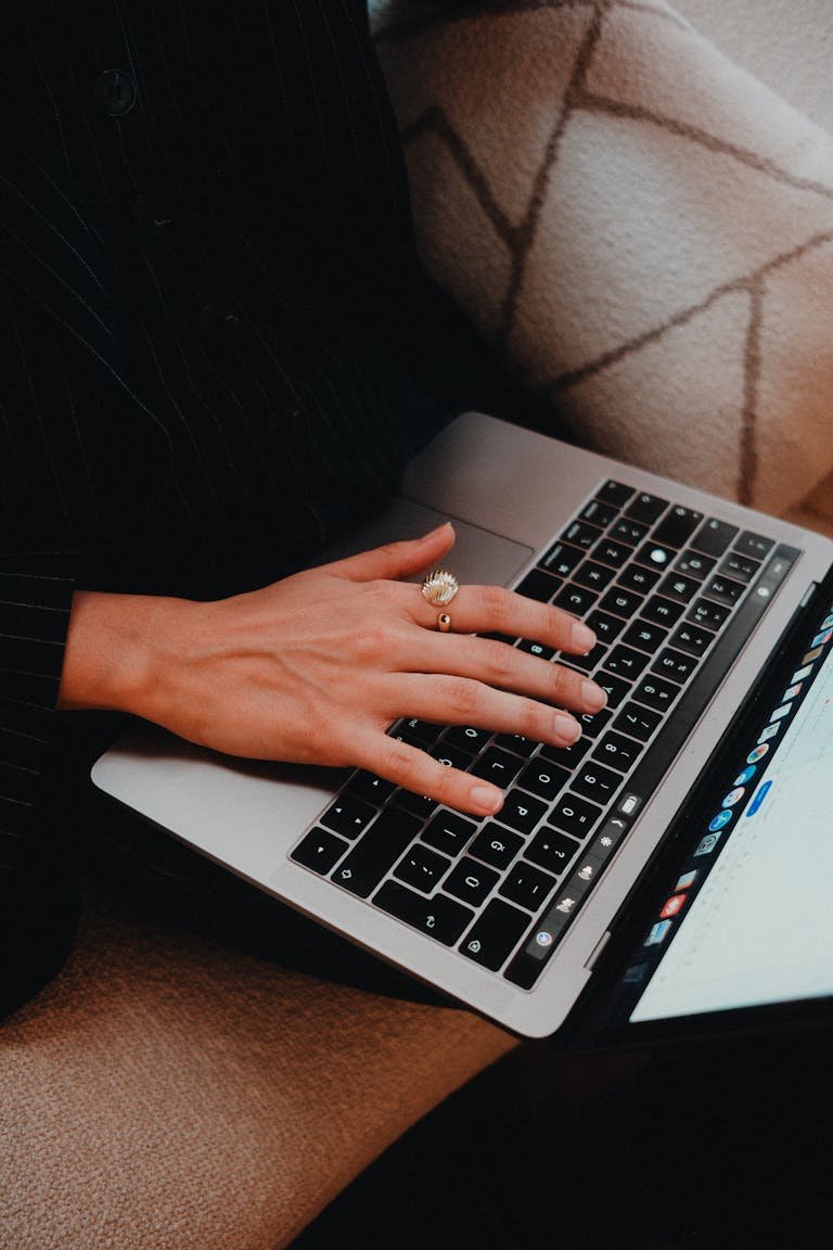 A close-up view of a person typing on a laptop keyboard with a focused hand.